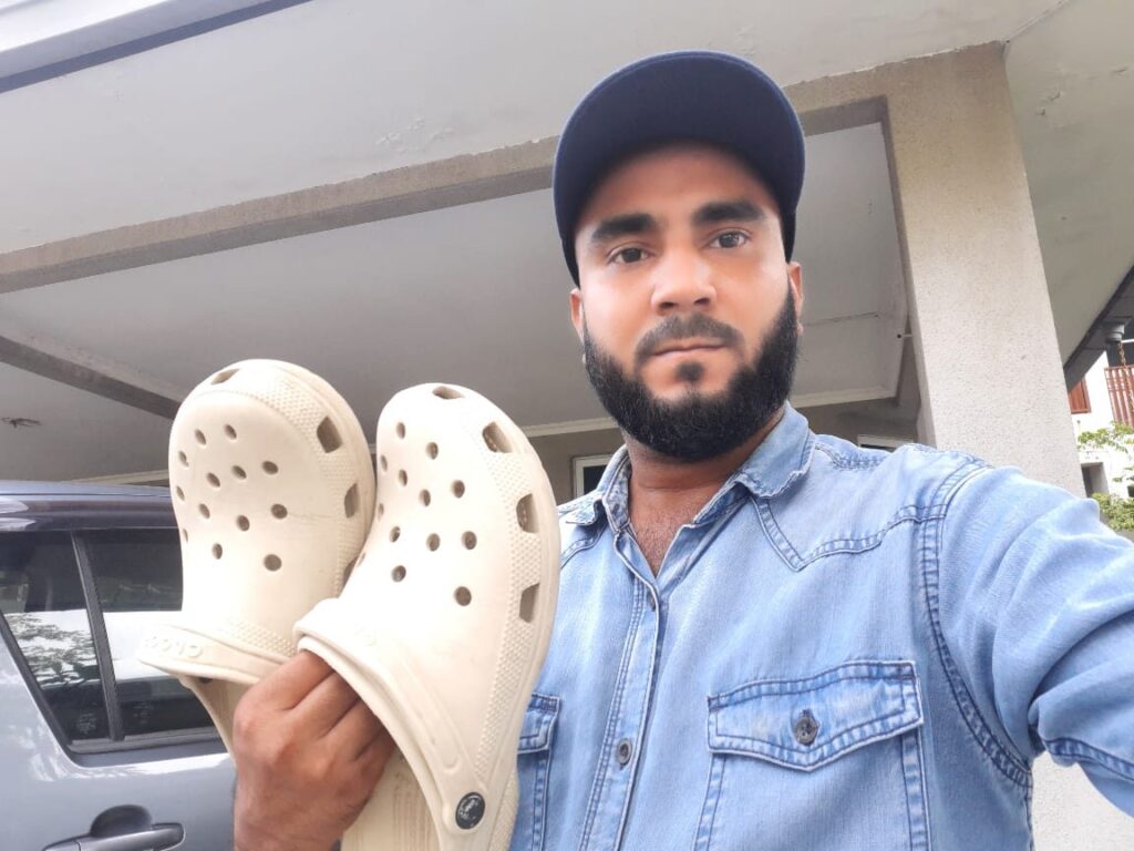 Holding a pair of Bone Crocs Classic Clogs