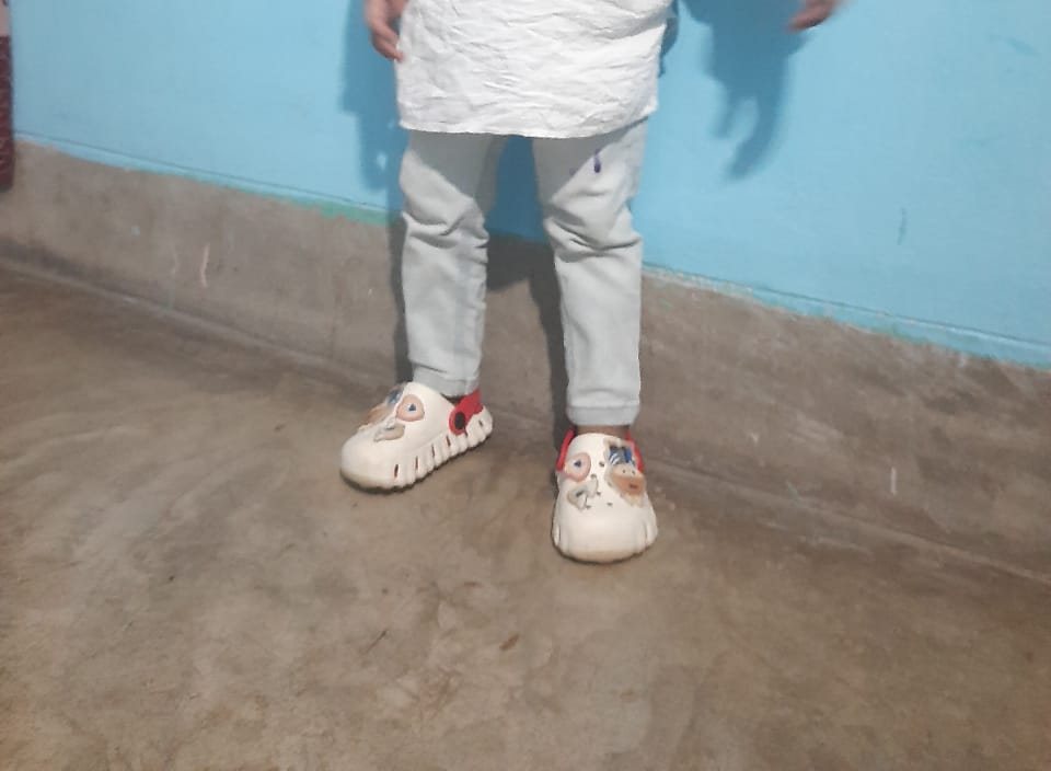 Boy standing in white and red kids clogs with charms