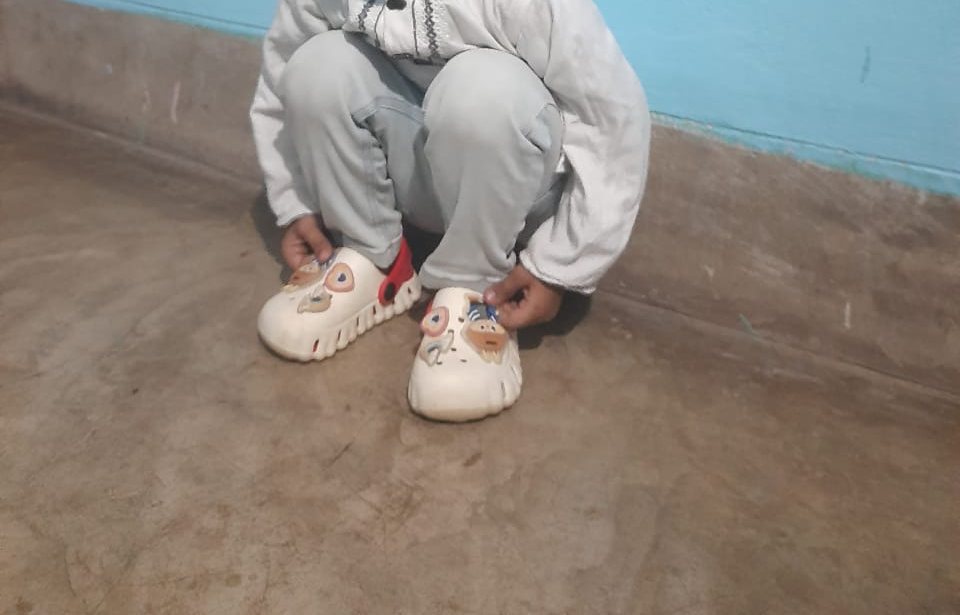 Child crouching in white and red kids clogs