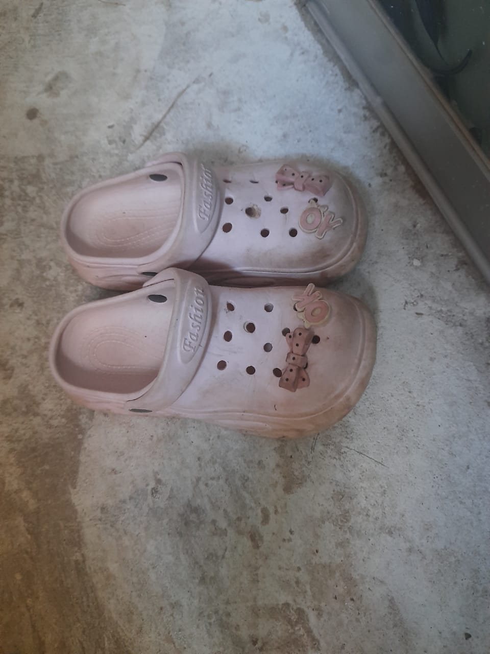 Worn pink kids clogs with Fashion printed on the strap and bow charms